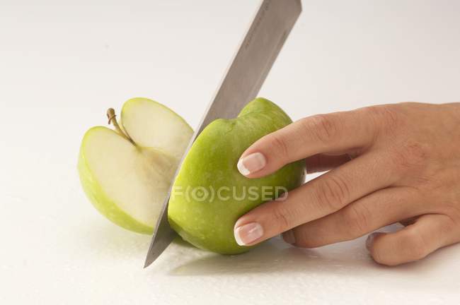 Жінка ріже зелене яблуко — стокове фото
