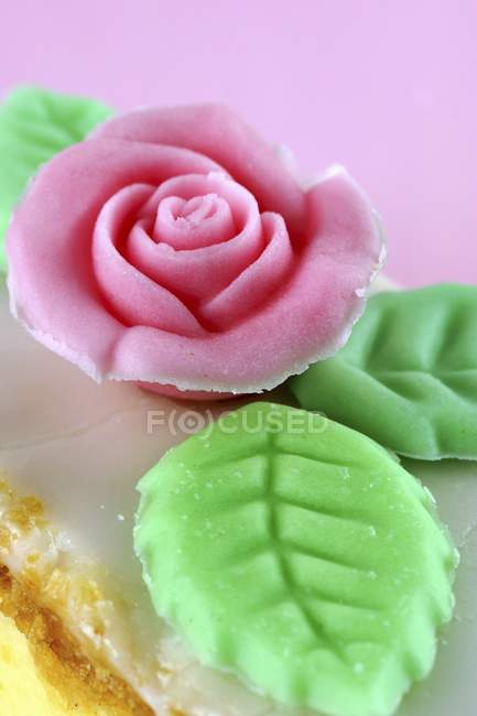 Сахарная роза на ломтике торта — стоковое фото
