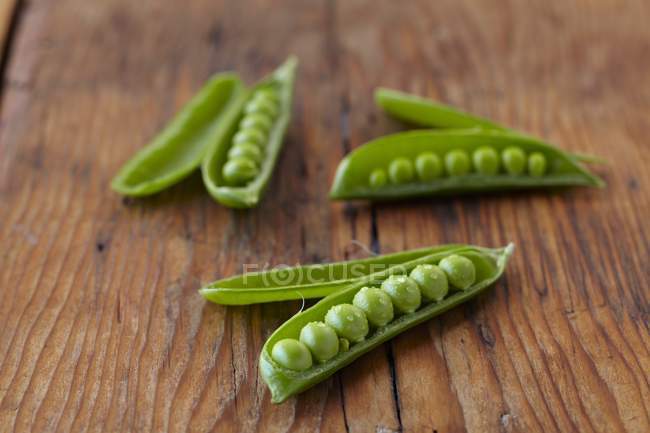 Opened pea pods on wooden table — Stock Photo