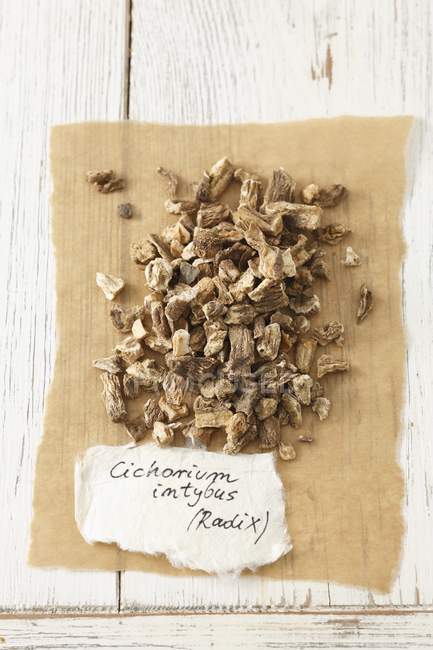 Vue surélevée de racine de chicorée séchée avec une étiquette sur papier — Photo de stock