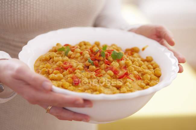 A woman carrying a bowl of chickpeas in hands, midsection — Stock Photo