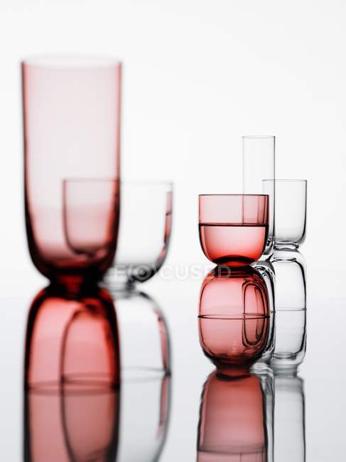 Two groups of glasses on a reflective white background — Stock Photo