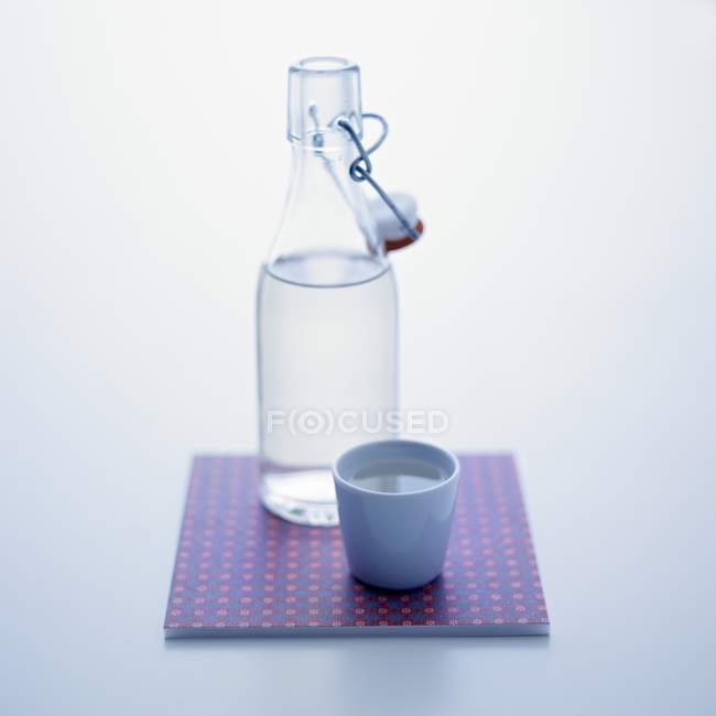 Closeup view of stoppered bottle and cup of water — Stock Photo