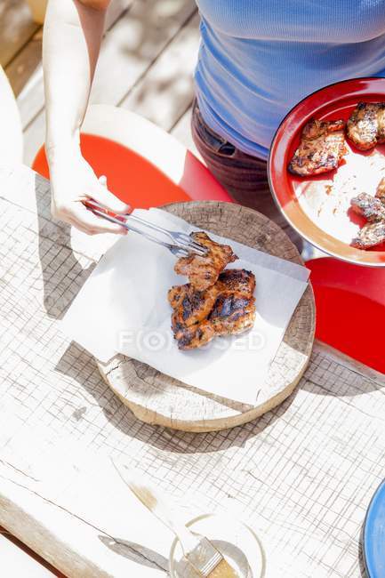 Vista diurna elevata della donna che sostituisce pezzi di pollo alla griglia — Foto stock