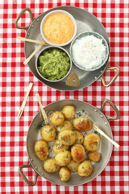 Baked potatoes with dips on plates over cloth — Stock Photo