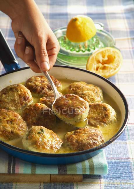 Cropped view of hand picking chicken meatball with spoon — Stock Photo
