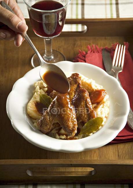 Elevated view of hand pouring chicken and mashed potato with red wine — Stock Photo