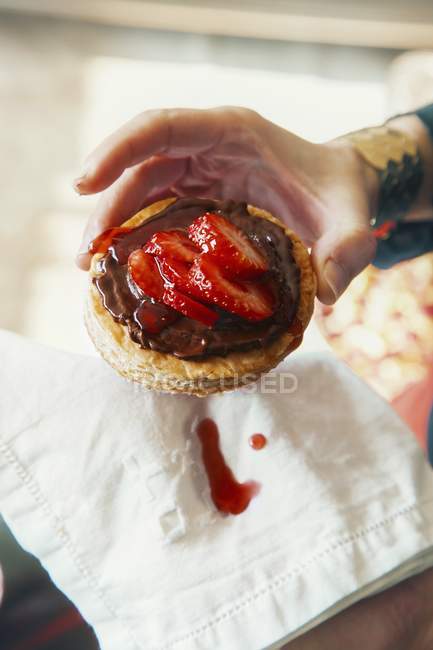 Hand holding chocolate torte with strawberries — Stock Photo