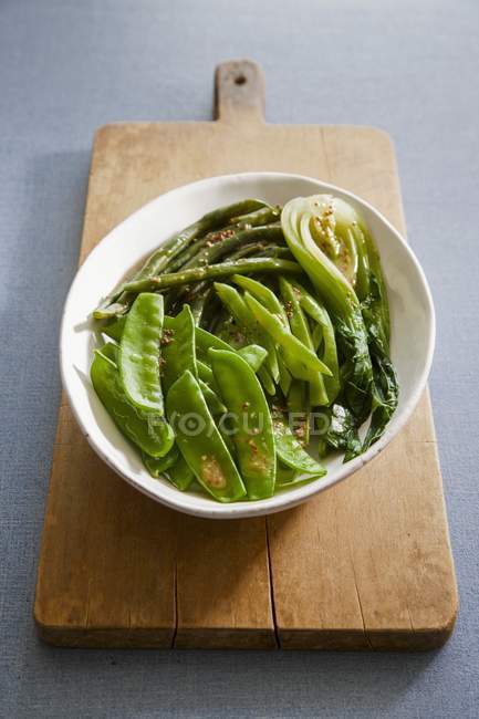 Buttered green vegetables in white bowl over wooden desk — Stock Photo