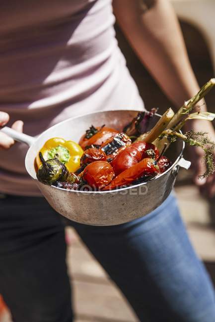 Verduras grelhadas em uma panela em mãos de homem — Fotografia de Stock
