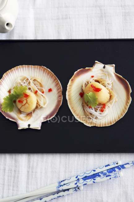 Top view of steamed scallops with herb on valves and black platter — Stock Photo