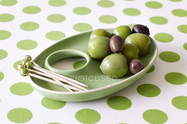 Green dish with olives and cocktail sticks — Stock Photo