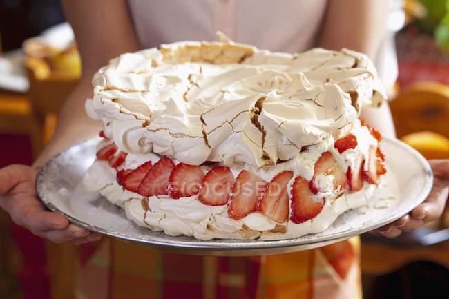 Gros plan vue recadrée de femme tenant gâteau Pavlova avec remplissage de citron crémeux et fraises — Photo de stock