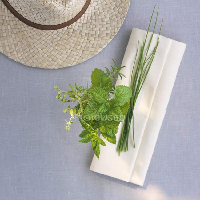 Top view of fresh herbs with a napkin and a straw hat — Stock Photo