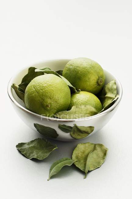 Limes with leaves in silver bowl — Stock Photo