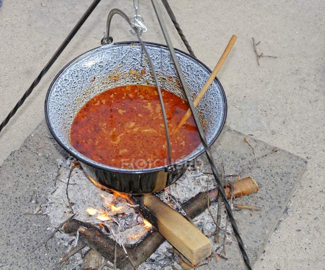Hungarian bean stew in a pot cooked over an open fire — Stock Photo