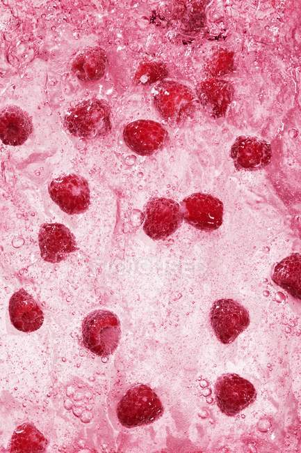 Framboesas em suco em rosa — Fotografia de Stock