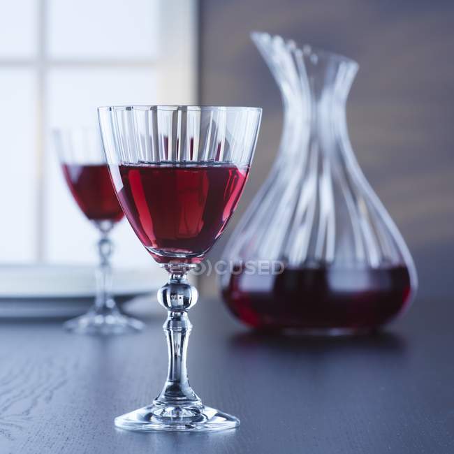Garrafa e copos de vinho tinto na mesa — Fotografia de Stock