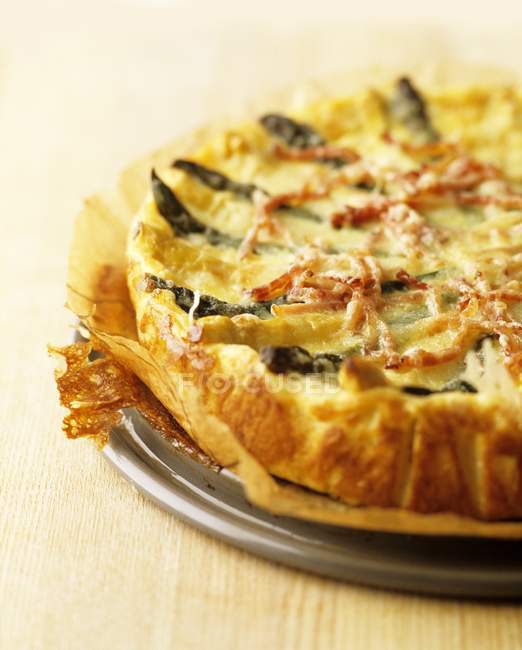 Asparagus quiche with strips of bacon  over wooden surface — Stock Photo
