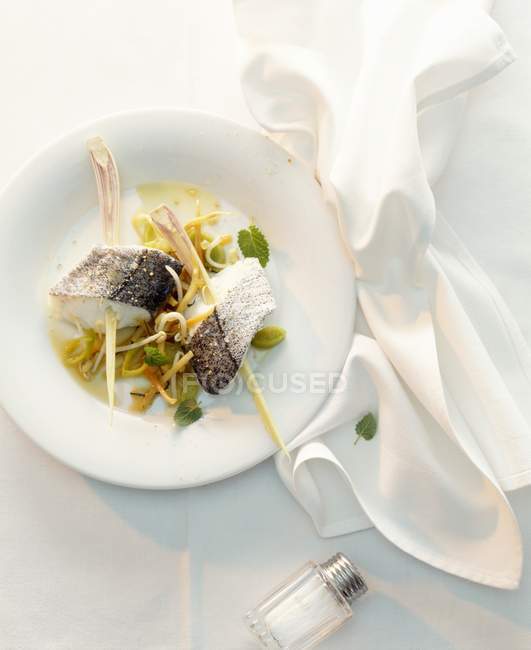 Рыба на шампуре из лимонной травы на ложе из овощей на белой тарелке с тканью — стоковое фото
