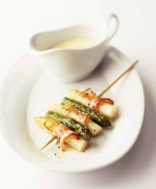 Spiedini di asparagi con pancetta su piastra bianca — Foto stock