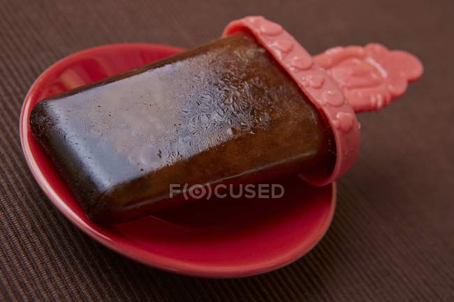 Primo piano vista del ghiacciolo di cola fatto in casa sul piatto rosso — Foto stock