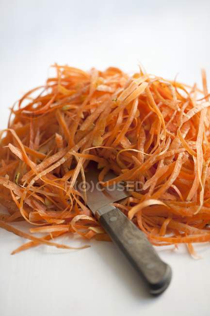 Montículo de peladuras de zanahoria con cuchillo - foto de stock