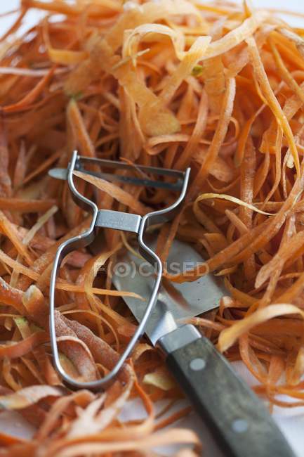 Peladuras de zanahoria con pelador - foto de stock