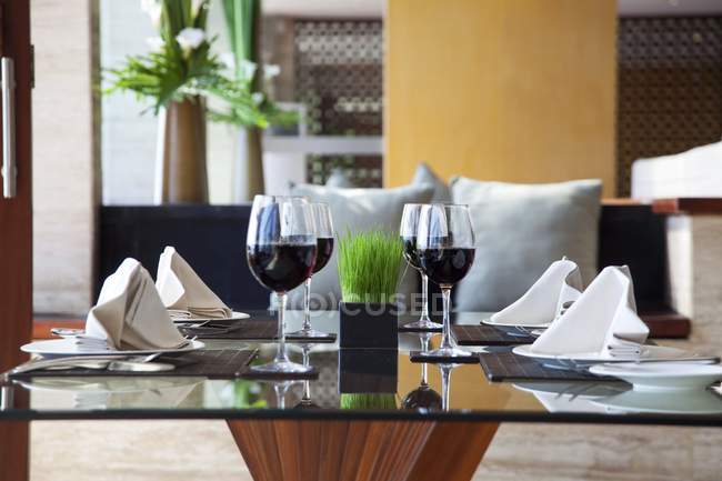 Une table dressée avec quatre couverts et des verres de vin rouge — Photo de stock