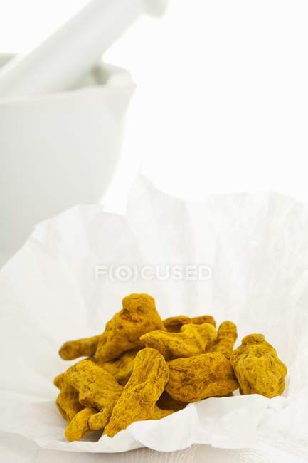 Closeup view of dried turmeric roots in white paper — Stock Photo
