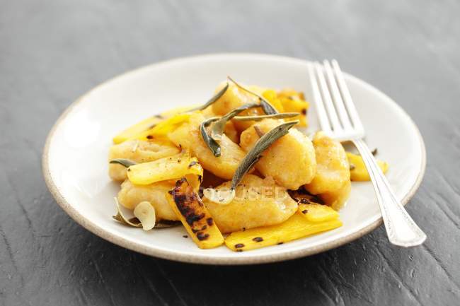 Squash gnocchi with butter, sage and grilled squash on white plate with fork — Stock Photo
