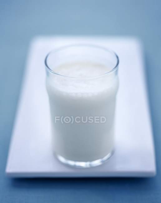 Vaso de leche en una fuente de servir blanca - foto de stock