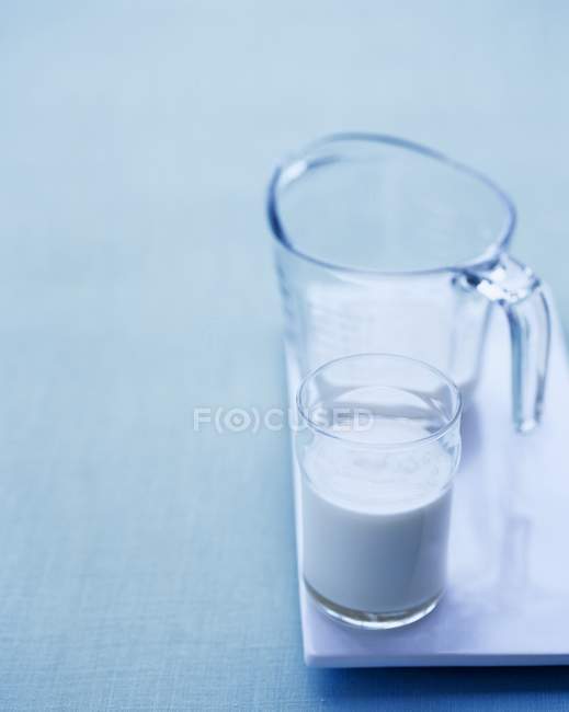 Glass of milk and a measuring jug — Stock Photo