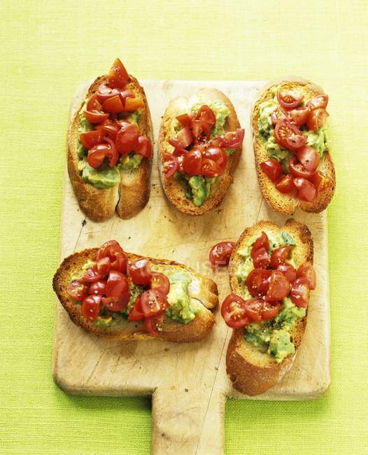 Avocado und Tomaten-Crostini auf Holztisch — Stockfoto