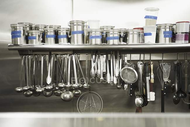Hanging metal tools and canisters of seasonings — Stock Photo