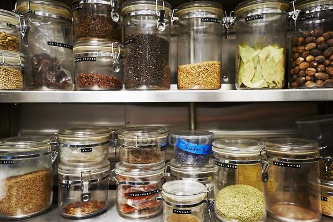 Assorted dried ingredients in storage containers on metal shelves — Stock Photo