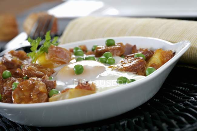 Испанская картошка с чоризо в кастрюле на белой тарелке — стоковое фото