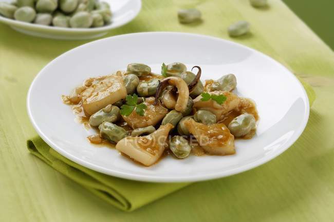 Cuttlefish with beans  on white plate  over green towel — Stock Photo