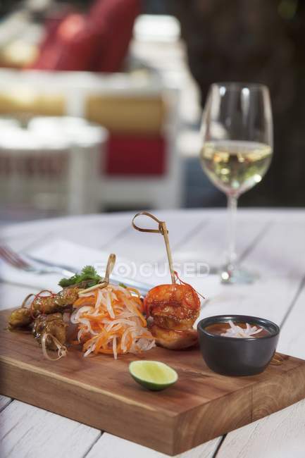 Elevated view of assorted Satay skewers with sauce and wine on a table — Stock Photo