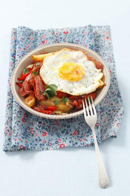 Bratkartoffeln mit Paprika, Speck und Spiegelei auf Teller über Handtuch mit Gabel — Stockfoto