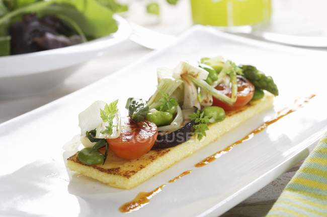 Verdure saltate su polenta con vinaigrette Romesco su piatto bianco — Foto stock