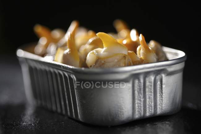 Closeup side view of cockles in tin on black surface — Stock Photo