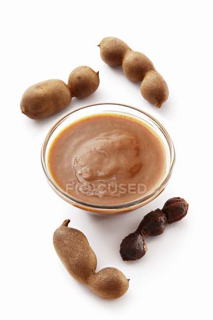 Tamarind concentrate in bowl and tamarinds — Stock Photo