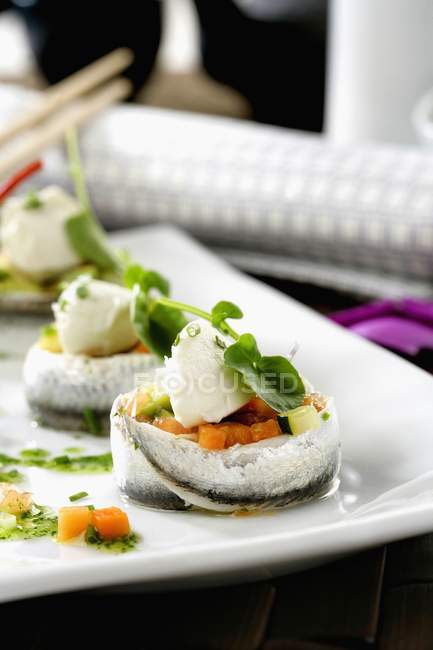 Fresh fish rolls with vegetables and herbs over white plate — Stock Photo