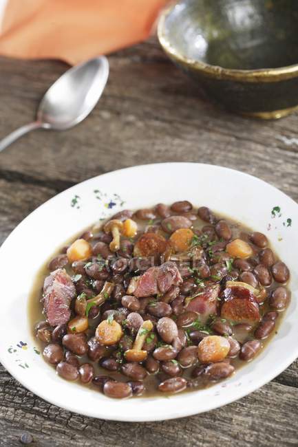 Black beans with sausage and mushrooms  on white plate — Stock Photo