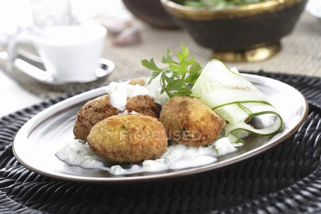 Falafel serving with sauce, cucumber and herbs — Stock Photo