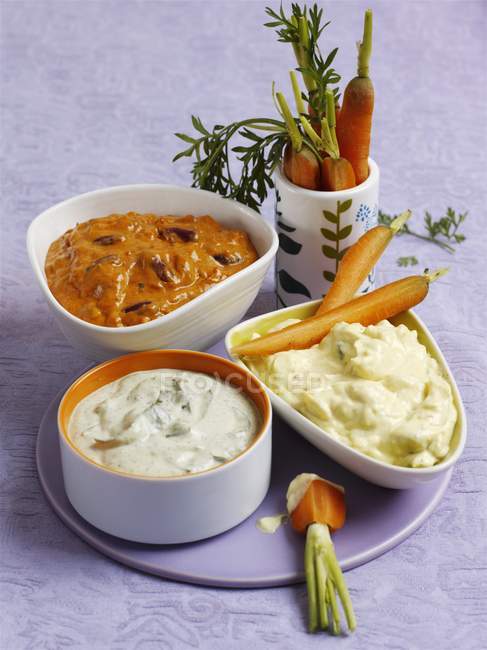 Carrots with assorted dips — Stock Photo
