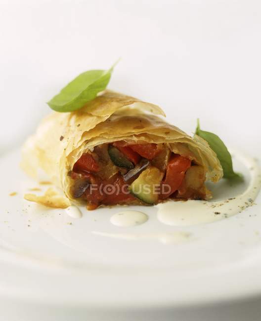 Strudel vegetal con tomates y calabacín en plato blanco - foto de stock