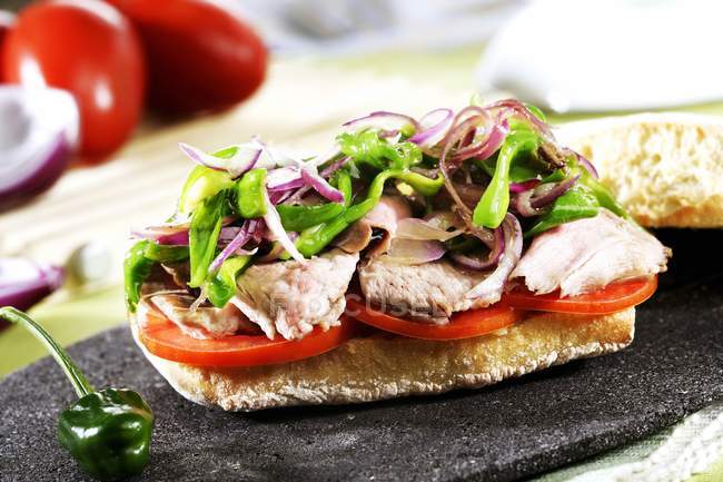 Toast topped with pork, tomatoes, peppers and onions — Stock Photo