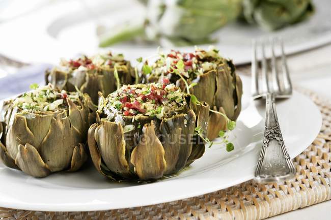 Stuffed baked artichokes on white plate with fork — Stock Photo